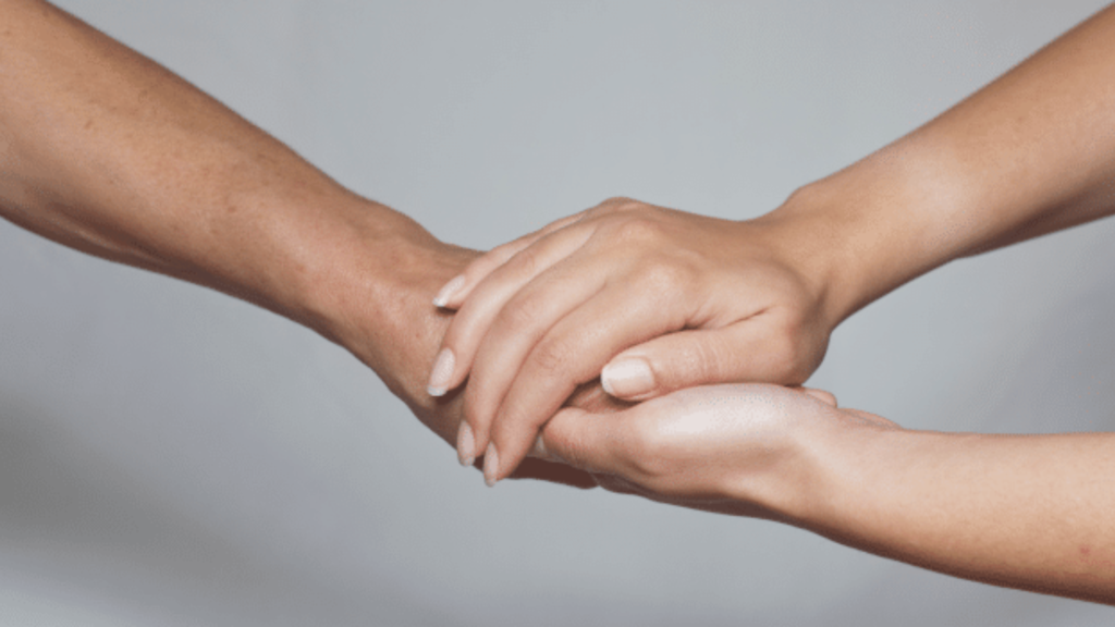 Dłonie dwóch osób trzymające się w geście wsparcia