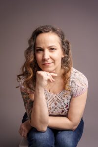 Agnieszka Walkowiak, specjalistka ds. marketingu i komunikacji, siedzi z ręką pod brodą i patrzy w obiektyw.