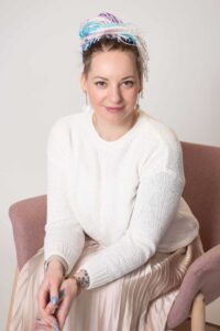 Karolina Dominiak-Piskorska, wiceprezeska Fundacji Przy Tobie, siedzi na krześle.