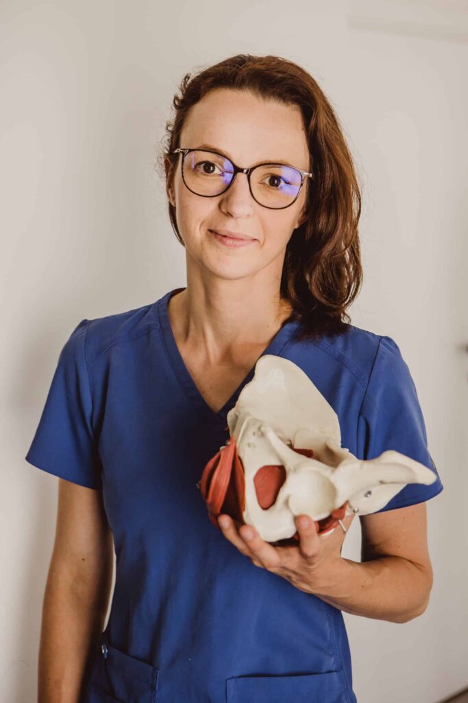 Magdalena Kutzner, fizjoterapeutka, stoi i trzyma model miednicy.