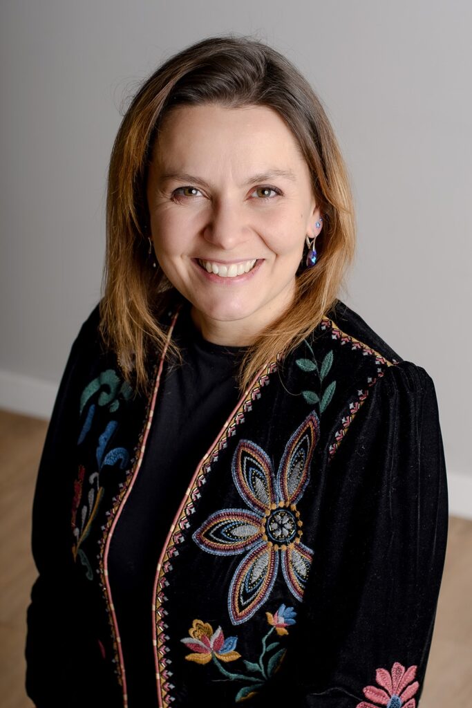 Anna Karczewska, psychoterapeutka, siedzi i uśmiecha się.