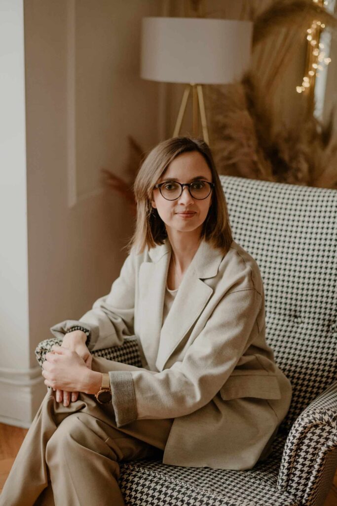 uzanna Filipowska, psychoterapeutka, siedzi na fotelu i trzyma kubek.